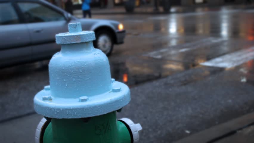 Wet Fire Hydrant covered in raindrops in busy metropolitan downtown city area