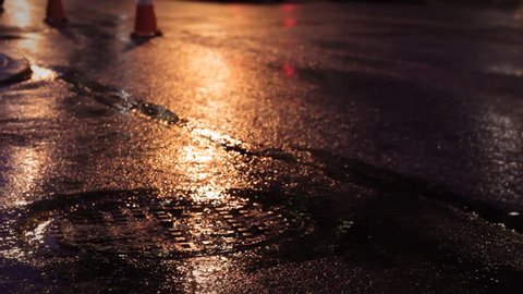 City Sewer in downtown area on rainy night in amber streetlight
