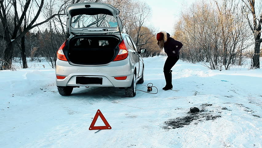 A girl is pumping up a flat tyre in winter