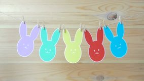 Close-up of colorful paper rabbits silhouette frames hanging on a cord against wooden background
