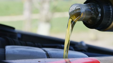 4K Close up of fresh oil being poured into a vehicle