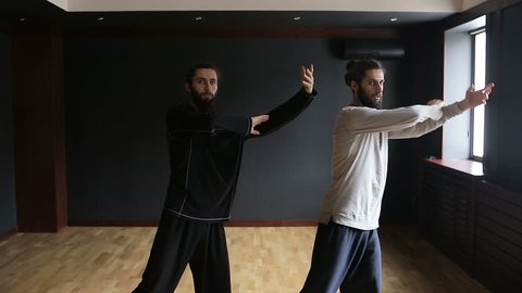 Twins brothers practice Tai Chi in the training hall