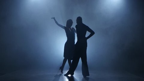Dance rumba performed by professional couple in smoky studio, silhouette