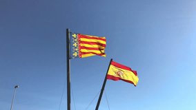 Flags of Spain and the autonomous community of Valencia waving in the wind against clear blue sky background