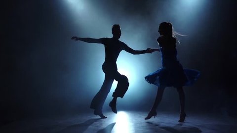 Professional couple of latinamerican dancers posing in smoky, slow motion