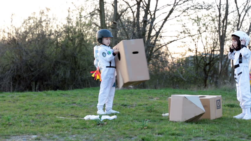 Two adorable children, boy brothers, playing in park on sunset, dressed like astronauts, imagining they are flying on the moon | Shutterstock HD Video #25458536
