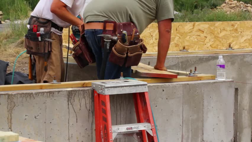 Construction workers using a nail gun to build the walls of a house