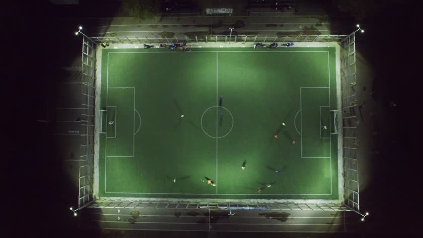 Upside down aerial view of football team practicing at night on soccer field