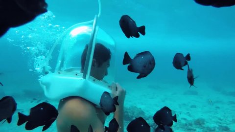 Male helmet diving underwater with tropical fish 