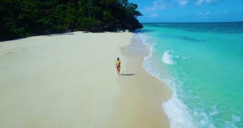 Female model walking on white sand beach