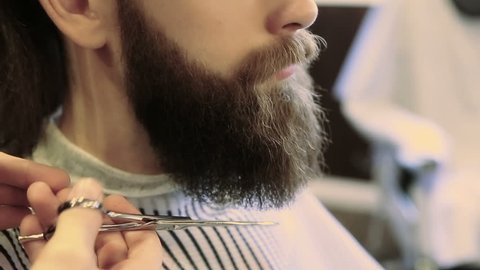 Barber combing beard with a pair of scissors at a barber shop