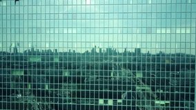 Aerial shot of modern office building windows reflecting cityscape on a sunny day. 4K video