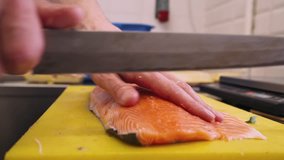 Cook cuts red fish into pieces, salmon, cooking. Close-up. 4k footage.
