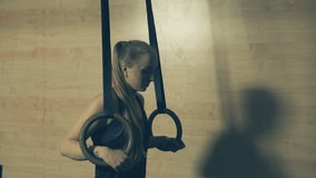 Woman doing pull-ups ring dips in a gym on gymnastic rings. Locked down real time 4K video