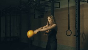 Beautiful young woman training with kettlebell weight in gym. Locked down real time 4K video.
