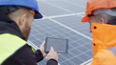 4K Technicians with tablet checking the panels at solar energy installation