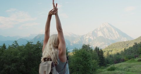 Woman with arms raised on top of mountain looking at view lifting arm up celebrating scenic landscape enjoying vacation travel adventure nature Alps Italy