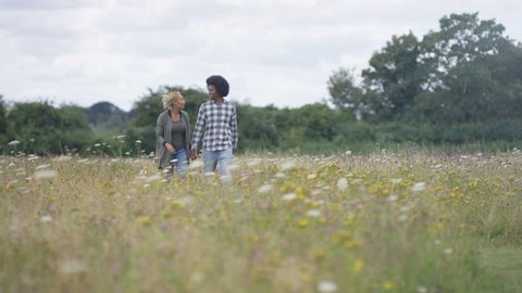 4K Happy couple walking in the countryside, man carrying girlfriend on his back