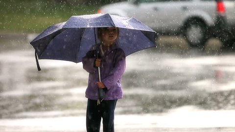 Little girl holding an umbrella in the rain