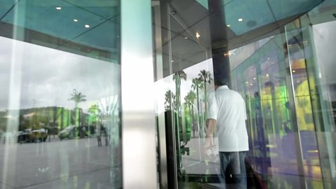 People using automatic revolving glass door or entering rotating spinning glass doorway. Entrance to the hotel,business ,exhibition or shopping center. People silhouettes and their reflection.