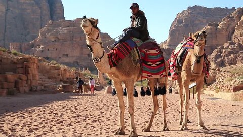 JORDAN, PETRA, DECEMBER 5, 2016: Jordanian on camel near The Colonnade Street in Petra, originally known to Nabateans as Raqmu - historical and archaeological city in Hashemite Kingdom of Jordan