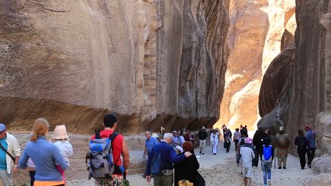 JORDAN, PETRA, DECEMBER 5, 2016: People in The Siq - narrow passage, gorge that leads to Red Rose City Of Petra, originally known to Nabataeans as Raqmu - historical and archaeological city in Jordan