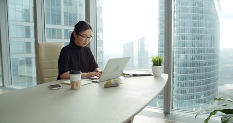 closeup Asian girl in a modern office, business correspondence using a laptop