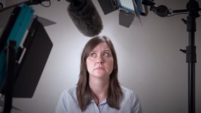 Scared business woman about to be interviewed on camera in a studio with video lights and microphone.