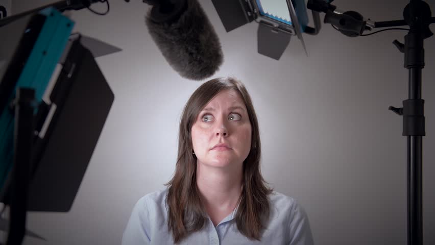 Scared business woman about to be interviewed on camera in a studio with video lights and microphone. Royalty-Free Stock Footage #25506959