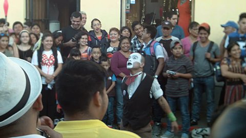 Antigua Guatemala / Guatemala, January 1, 2017: A street performer acts in the middle of a crowd of people on 5 Avenida Norte.