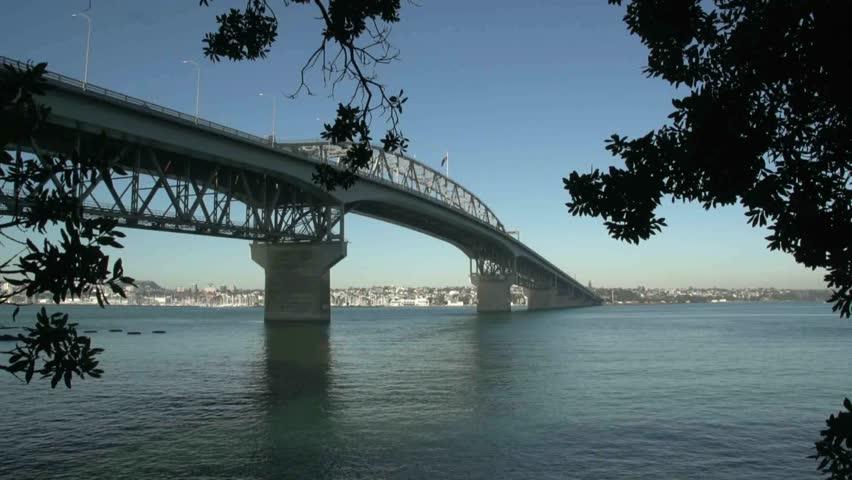 View through trees of Auckland harbour bridge, which has shaped Auckland's