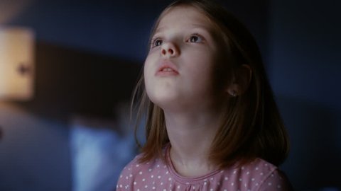 Curious Little Girl in Her Bedroom at Night, Stands on Tiptoe and Looks out of the Window. Shot on RED EPIC-W 8K Helium Cinema Camera.