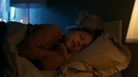 Sweet Little Girl Sleeps in Her Bed at Night, Her Mother Tucks Her Blanket in. Shot on RED EPIC-W 8K Helium Cinema Camera.