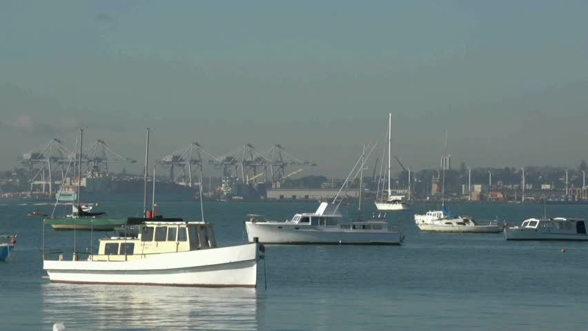 View over boats moored in Auckland harbour to commercial container wharf and