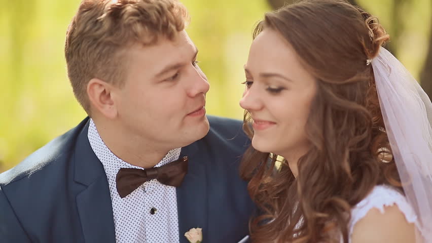 Bride and groom on their wedding day, during a walk in nature. Happy groom tenderly kissing bride