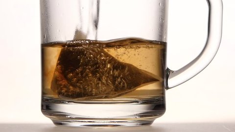 Pyramid tea bag in cup is poured over boiling water