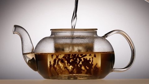 Leaves of green tea are brewed in teapot, white background