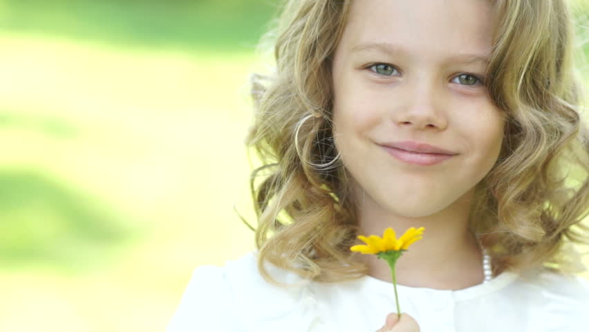 Portrait of a girl sniffing a yellow flower
