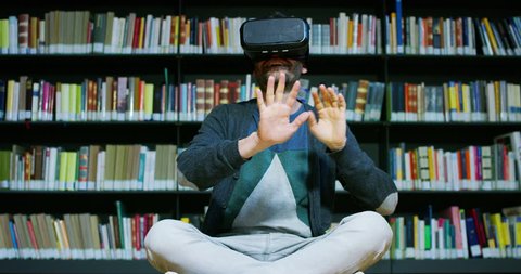 A beautiful young man in a library travels in a virtual futuristic world with augmented reality. Concept: educational, future, library, and immersive technology.