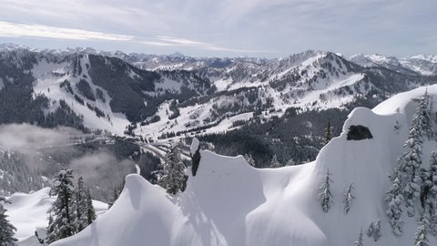 Amazing Aerial Reveal of Highway to Winter Ski Resort with Snowy Mountain Range Peaks