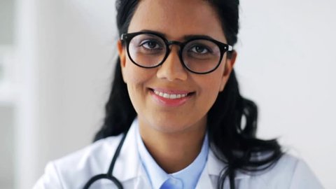 people, medicine, healthcare and facial expression concept - face of happy smiling young doctor or woman in glasses