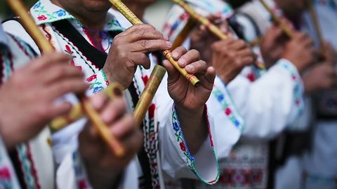 People in romanian traditional costumes singing at wooden flutes