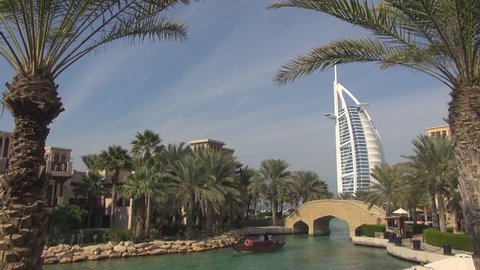 DUBAI, UAE - JANUARY 25, 2014, Touristic abra boat sail in Burj Al Arab exotic garden lake , city emblem
