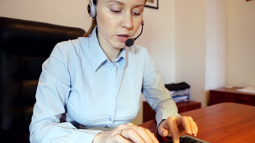 Businesswoman in headphones speaking and sitting on the workdesk 