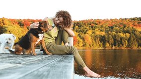 Woman and dog relaxing on the dock. Slow motion video. Autumn colors, unstaged situation with candid model and her dog. Relaxation and friendship concepts.