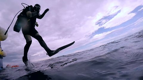 Scuba Diver Jumping into the Ocean. In slow motion a scuba diver jumps into water.  Scuba Diver Jumping Off Dive Boat.
