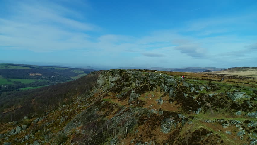 People hiking up in the hills rocky mountain cliff aerial view