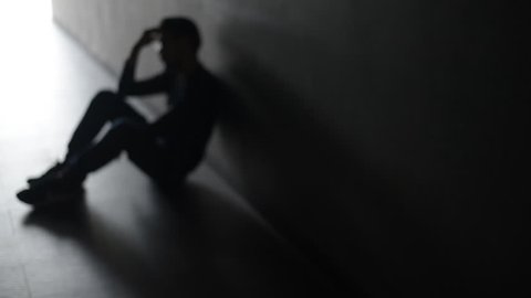 Asian troubled man in an empty room is hopeless. Blurred and silhouette shot.