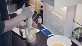 Young man preparing vegetable food at kitchen and watching video at smartphone