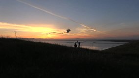 Silhouette of family flying kite together at sunset slow motion HD